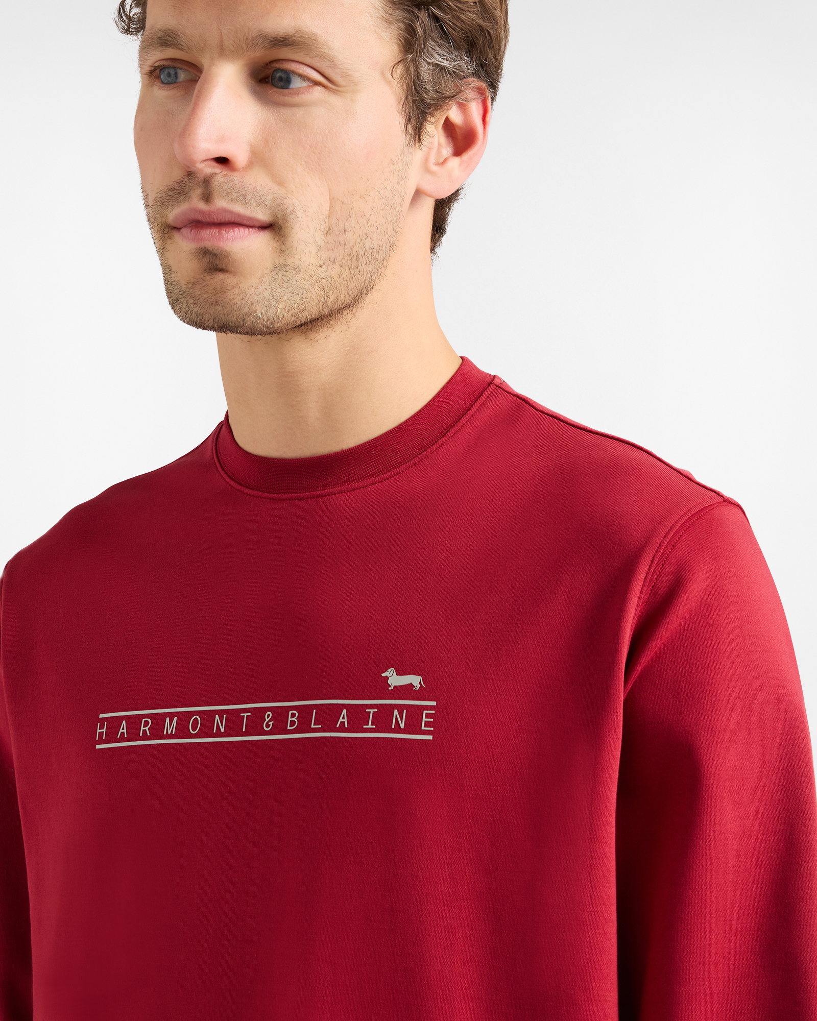 Hombre con sudadera roja con logo de Harmont & Blaine en el pecho.